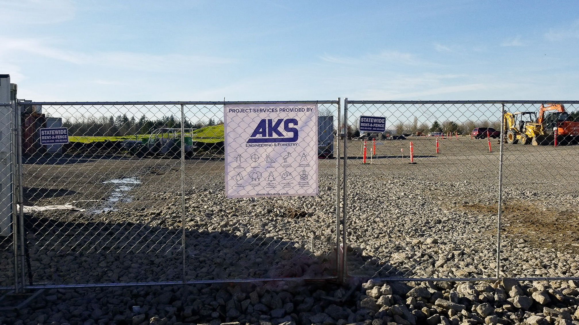 An AKS sign on a chain-link fence at a job site