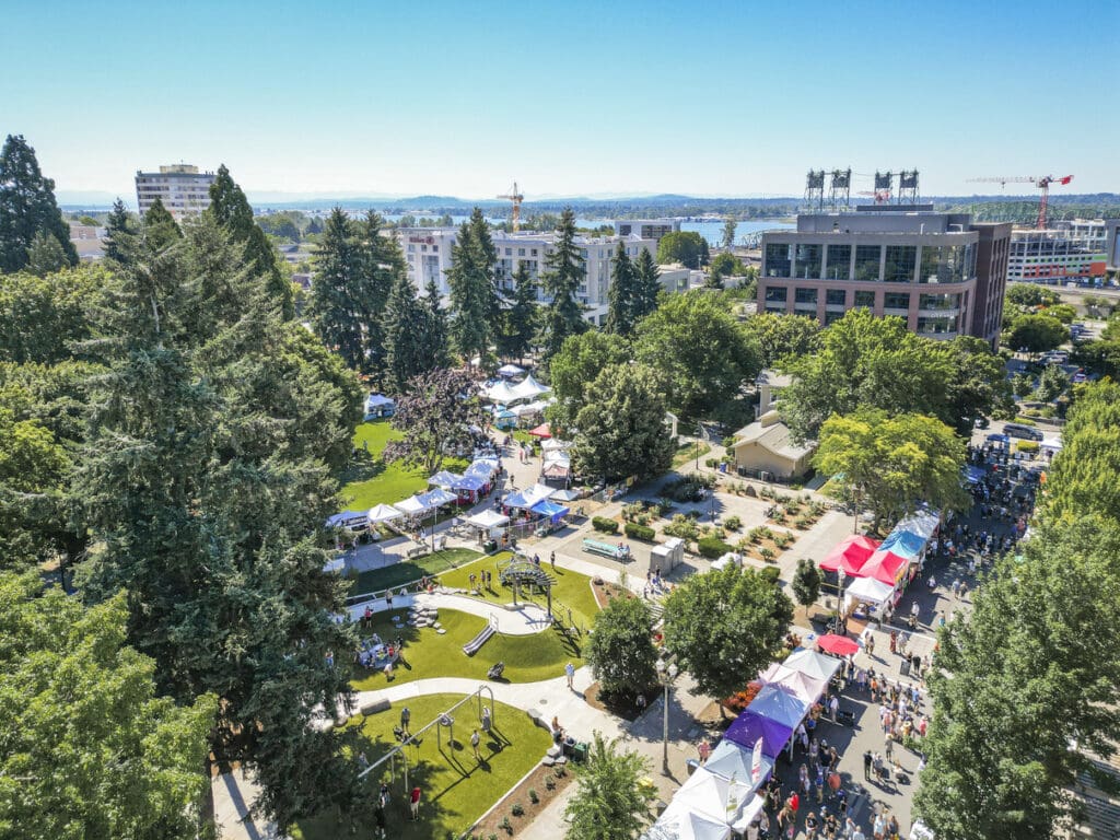 An aerial view of Esther Short Park in Vancouver, Washington, featuring a playground, vendor tents, walking paths, and landscaping